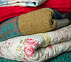 Pile of different coloured and textured quilts